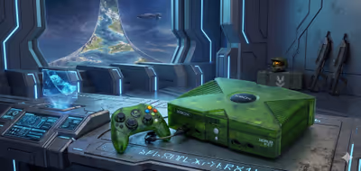 A translucent green original Xbox console and matching controller sitting on a futuristic desk, with a space station window showing a Halo ring in the background.